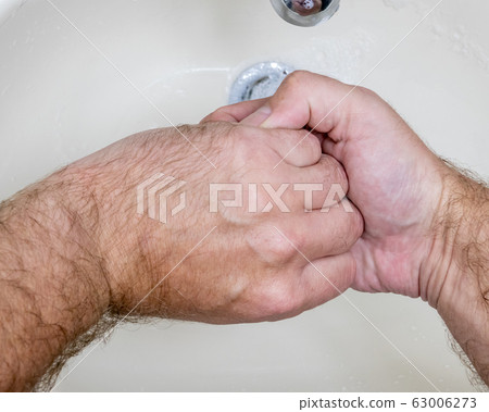 Man washing hands close-up from above 63006273