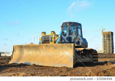 Bulldozer during land clearing and foundation digging at large construction site 63006498