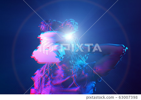 Woman is using virtual reality headset. Neon light studio portrait. Image with glitch effect. 63007398