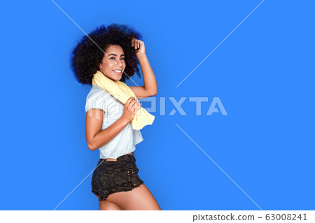 Freestyle. Mulatto girl walking isolated on blue with towel around neck smiling toothy 63008241