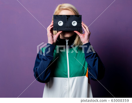 Style blonde woman in 80s clothes with VHS 63008359