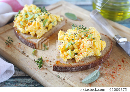 Scrambled eggs on slice of rye bread for breakfast Scrambled eggs on slice of rye bread for breakfast 63009875