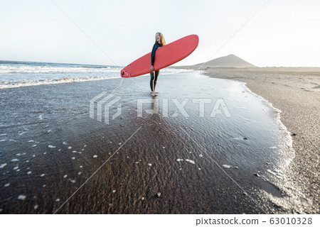 Young surfer with surfboard on the beach Young surfer with surfboard on the beach 63010328