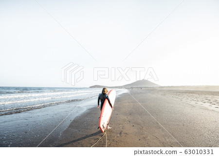 Young surfer with surfboard on the beach Young surfer with surfboard on the beach 63010331