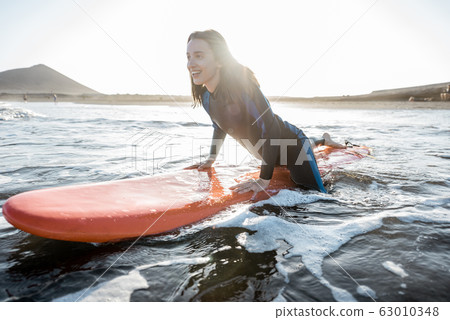 Woman surfing in the sea Woman surfing in the sea 63010348