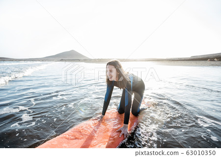 Woman surfing in the sea Woman surfing in the sea 63010350