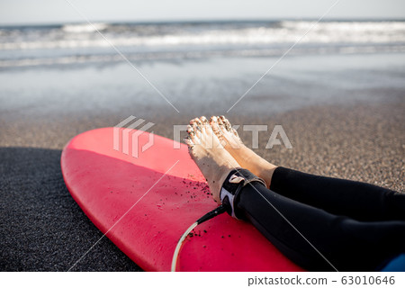 Surfer lying on surfboard on the sandy beach 63010646