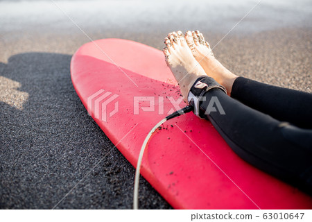Surfer lying on surfboard on the sandy beach 63010647