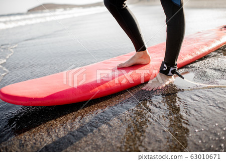 Surfer with surfboard on the sandy beach Surfer with surfboard on the sandy beach 63010671