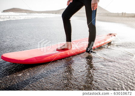 Surfer with surfboard on the sandy beach Surfer with surfboard on the sandy beach 63010672