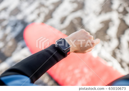 Surfer using smart watch 63010673