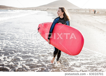 Young surfer with surfboard on the beach 63010701