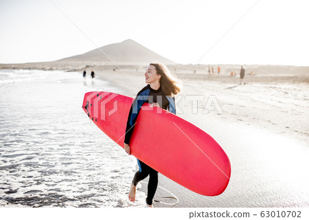 Young surfer with surfboard on the beach Young surfer with surfboard on the beach 63010702