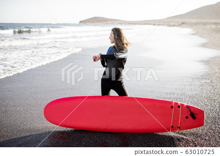 Young surfer with surfboard on the beach 63010725