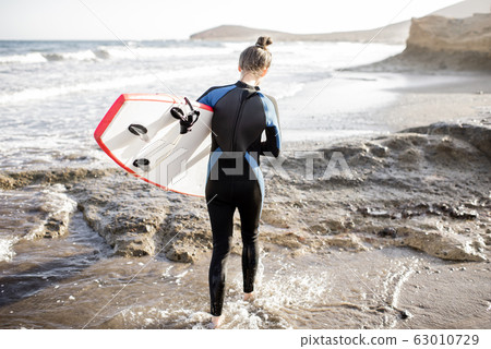 Young surfer with surfboard on the beach 63010729