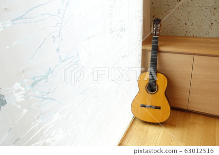 A room with a classical guitar in the light through the curtains 63012516