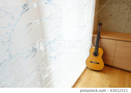 A room with a classical guitar in the light through the curtains 63012521