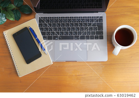 Laptop, smartphone, coffee, notebook and green placed on wood grain desk 63019462