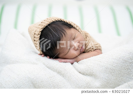 Adorable newborn baby peacefully sleeping on a white blanket. 63021027