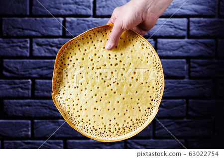 Woman holds martabak manis in front of black wall Woman holds martabak manis in front of black wall 63022754