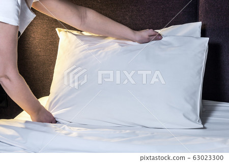 female hands corrected pillow on the bed 63023300