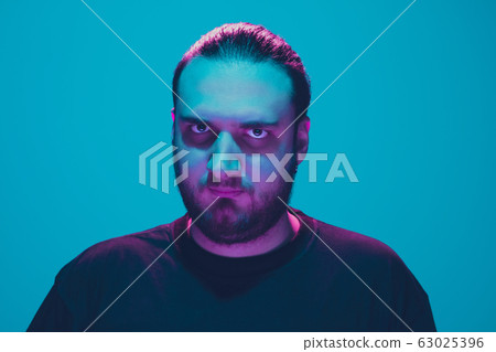 Portrait of a guy with colorful neon light on blue background - cyberpunk concept Portrait of a guy with colorful neon light on blue background - cyberpunk concept 63025396