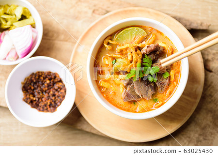 Spicy curry noodles soup with coconut milk and beef eating by chopsticks,Northern Thai food Spicy curry noodles soup with coconut milk and beef eating by chopsticks,Northern Thai food 63025430
