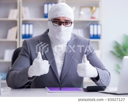 Bandaged businessman worker working in the office doing paperwor 63027127