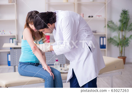 Young arm injured woman visiting young doctor traumatologist 63027263