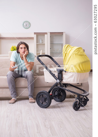 Young man looking after baby in pram 63027295