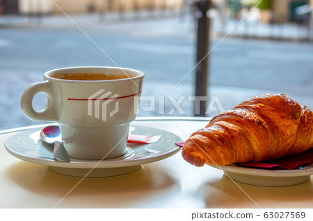 Cup of Coffee and a Croissant on a Table of a 63027569