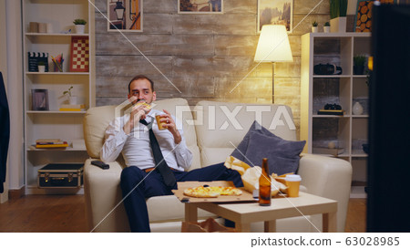 Tired businessman in suit sitting on couch laughing Tired businessman in suit sitting on couch laughing 63028985
