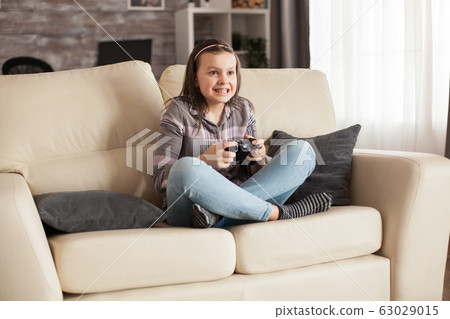 Focused little girl with braces playing video games 63029015