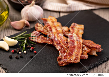 Closeup of slices of crispy hot fried bacon Closeup of slices of crispy hot fried bacon 63030028
