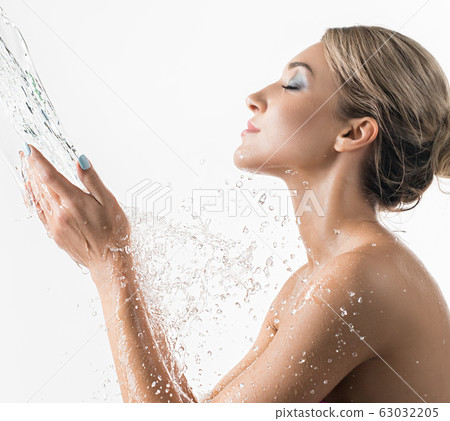 Pretty girl catching water stream in her hands Pretty girl catching water stream in her hands 63032205