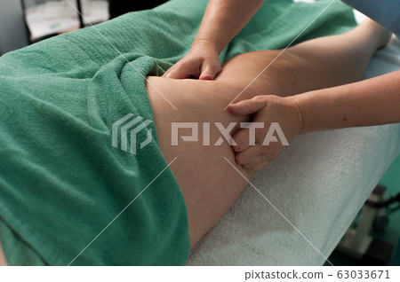 Woman massage the legs of a young unknown woman Woman massage the legs of a young unknown woman 63033671