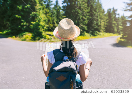 Hiking girl traveler with backpack checks map Hiking girl traveler with backpack checks map 63033869