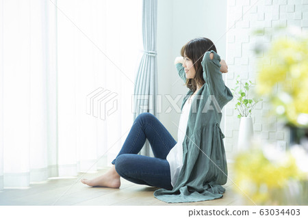 Young woman, stretching, sitting Young woman, stretching, sitting 63034403
