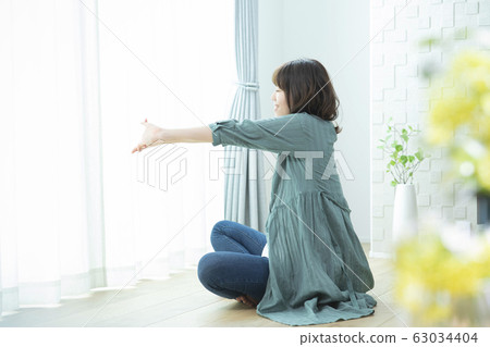 Young woman, stretching, sitting Young woman, stretching, sitting 63034404