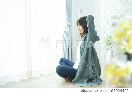 Young woman, stretching, sitting Young woman, stretching, sitting 63034405
