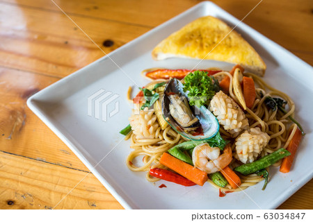 Seafood spaghetti, shrimp, squid, vegetables Asian cuisine is popular on white plates on wooden floors. 63034847