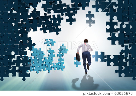 Businessman breaking the wall of jigsaw puzzle Businessman breaking the wall of jigsaw puzzle 63035673