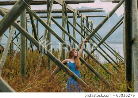 Young woman in blue dress holding tree trunk, Young woman in blue dress holding tree trunk, 63036279