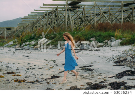 Young woman in blue dress walking on white sand, Young woman in blue dress walking on white sand, 63036284