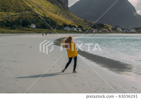 Back of girl in yellow jacket on the white sand Back of girl in yellow jacket on the white sand 63036291