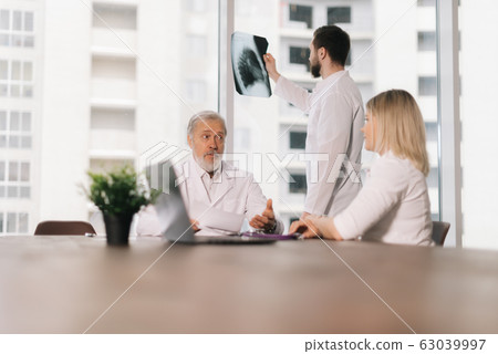 Young doctor stands by the window with an X-ray Young doctor stands by the window with an X-ray 63039997