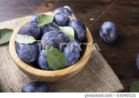Ripe plums in a wooden bowl. Fresh fruits. Ripe plums in a wooden bowl. Fresh fruits. 63040528