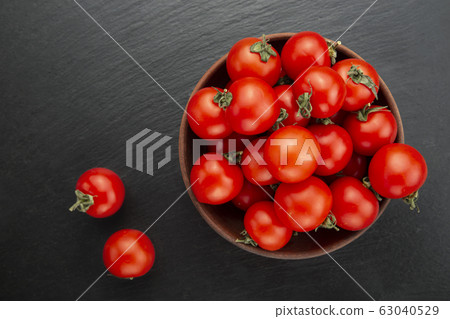 Fresh tomatoes in a bowl on a black background. Fresh tomatoes in a bowl on a black background. 63040529