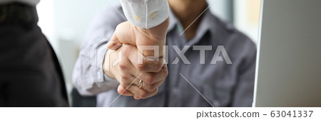 Two male clerks shaking hands at workplace close-up Two male clerks shaking hands at workplace close-up 63041337