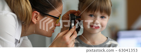 Pediatrician examines ear of sick child in office Pediatrician examines ear of sick child in office 63041353